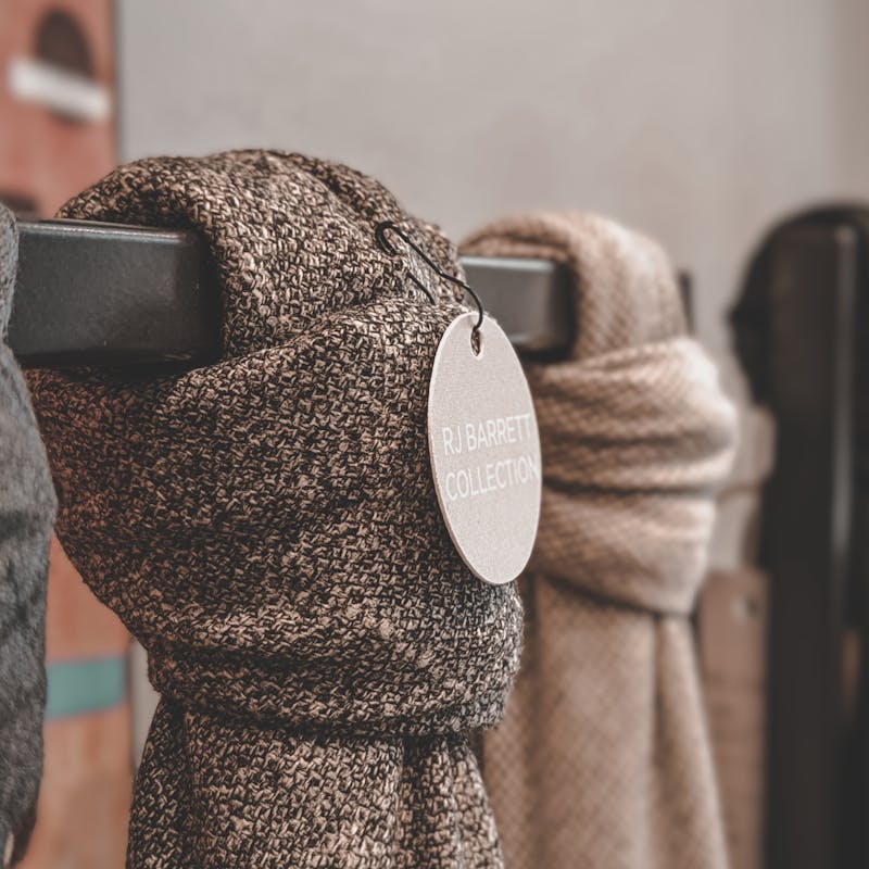 Fashion-forward wool scarves elegantly displayed in store, highlighting the RJ Barrett collection.