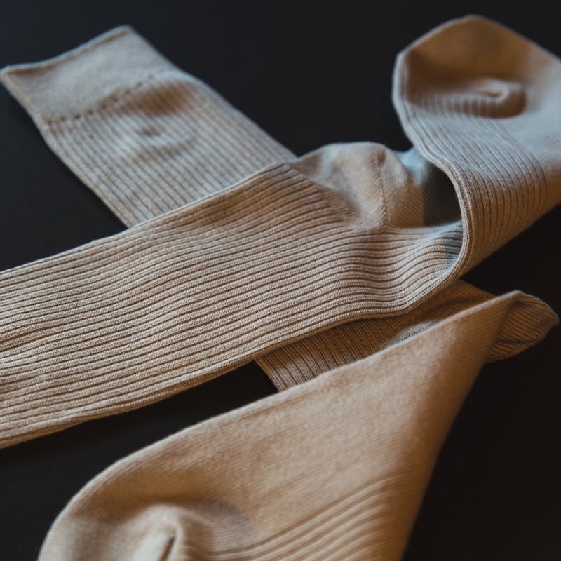 From above of pair of socks made of soft cotton cloth placed on black background